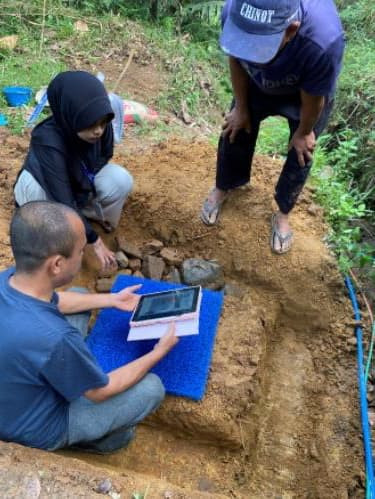 Proses pemantauan dan diskusi teknis pembangunan bak air oleh mahasiswa PPG UNPAS dan tokoh masyarakat setempat.