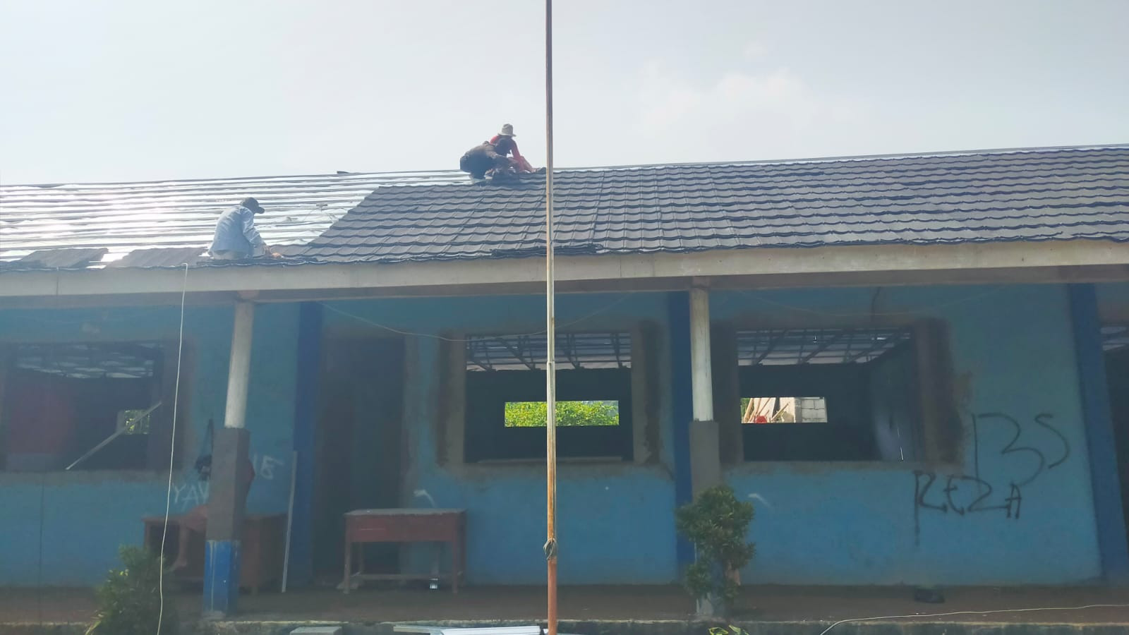 Pekerja Atap SMP Gunung Mulya Memasang Genteng Tanpa Perlengkapan APD K3.